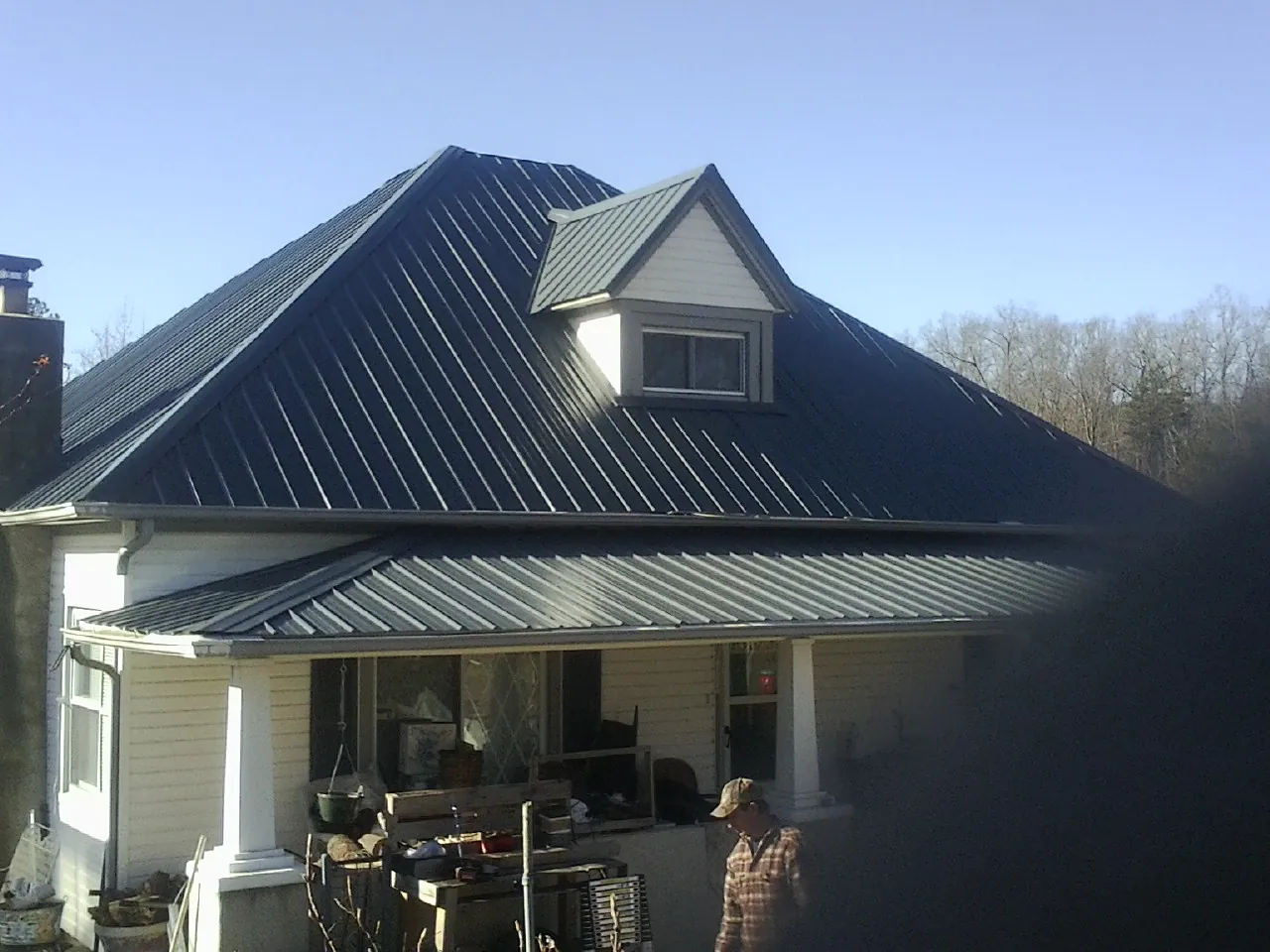 Dark blue standing seam metal roof with a dormer above a front porch in Arbovale