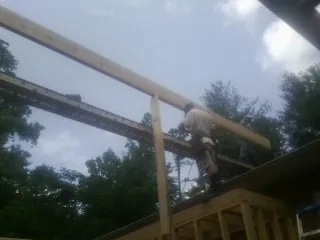 Carpenter setting a ridge beam over a new addition frame — Ice Dam Removal by Roofing Brothers in Arbovale
