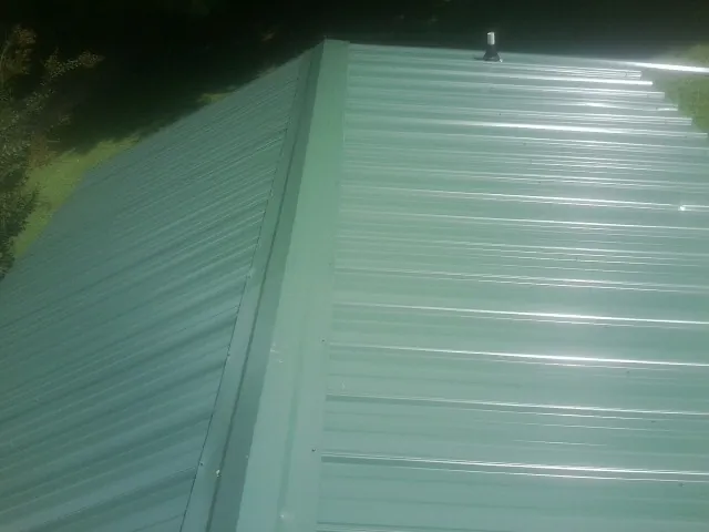 New green metal panels meeting at the ridge of a roof — Flat Roof Repair work by our crew in Arbovale