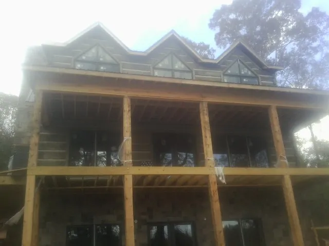 Dormers and porch framing on a large log home under construction — Roof Coating work by our crew in Arbovale