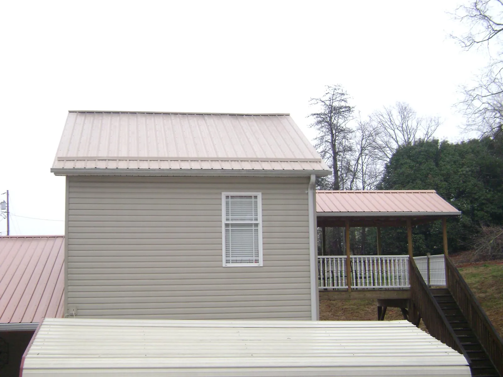 Tan metal roofs on a two story addition and attached porch, from a Roof Replacement job in Arbovale