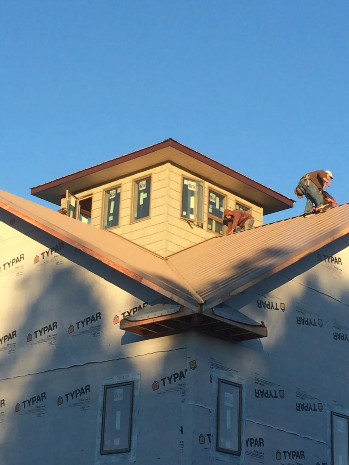Roofers working around a rooftop cupola on a new metal roof at sunset — Roof Waterproofing in Arbovale by Roofing Brothers